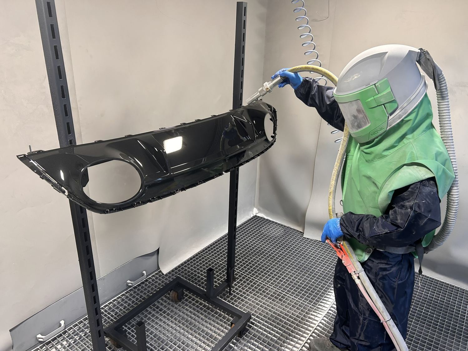 Mitarbeiter bereitet ein Kunststoff-Bauteil im Schutzanzug mit dem Cartec BigBoxBlower im Wirbelstrom-Verfahren vor